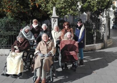 Grupo de mayores posando enfrente de una estatua.